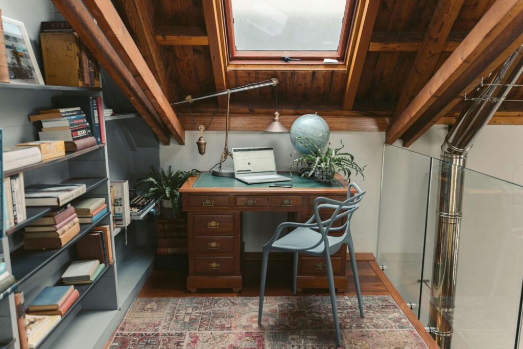 cozy attic workspace with a rustic wooden ceiling featuring exposed beams and a skylight