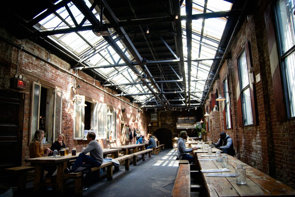 Warehouse-style bar with bench seating area illuminated by skylights